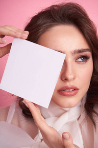  Young girl on a pink background holds an empty sheet to fill