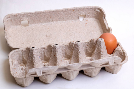 一个鸡蛋装在灰色背景的纸盒里照片