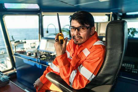 在船或船的驾驶台上的菲律宾甲板官员。他正在用GMDSS甚高频无线电讲话