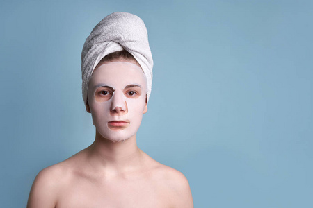 teenage girl with clay mask on the face blue background 