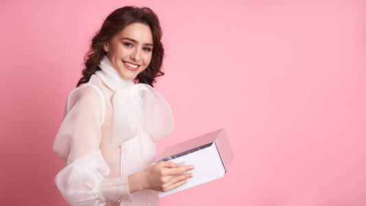  Young girl holding a pink box on a pink background