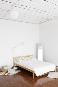 卧室的内部。宽敞明亮清新的卧室，白色墙壁和木地板，装饰有小地毯柳条座椅和落地灯