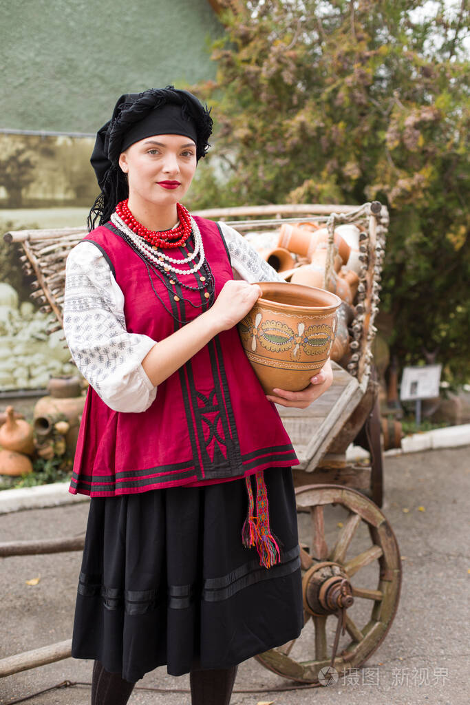穿着民族服装的漂亮女孩.手里拿着一个古老的罐子.