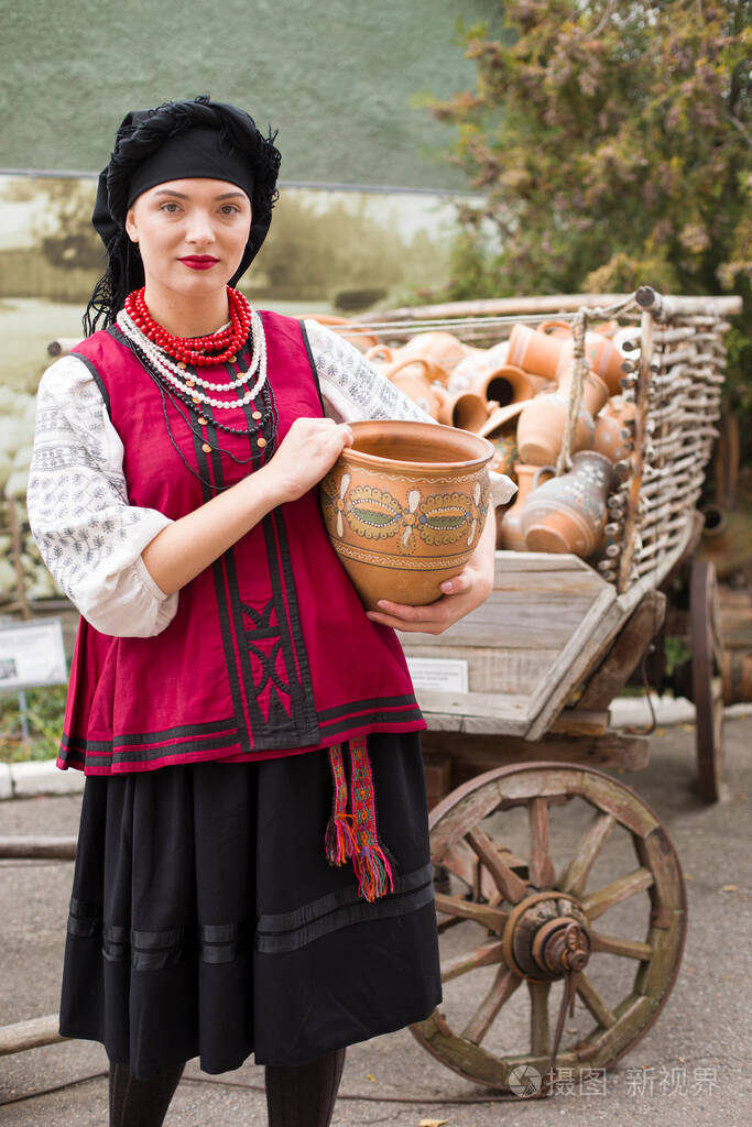 穿着民族服装的漂亮女孩手里拿着一个古老的罐子19世纪末的古董服装