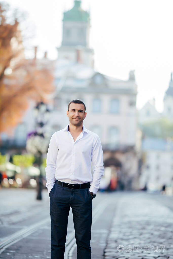 穿着衬衫戴着眼镜站在城市街道上的年轻人