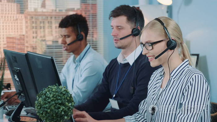 女客服在繁忙的呼叫中心与国际客户交谈的中景