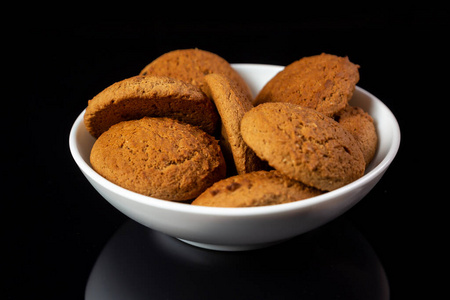 Appetizing oatmeal cookies in a white plate closeup on a black 