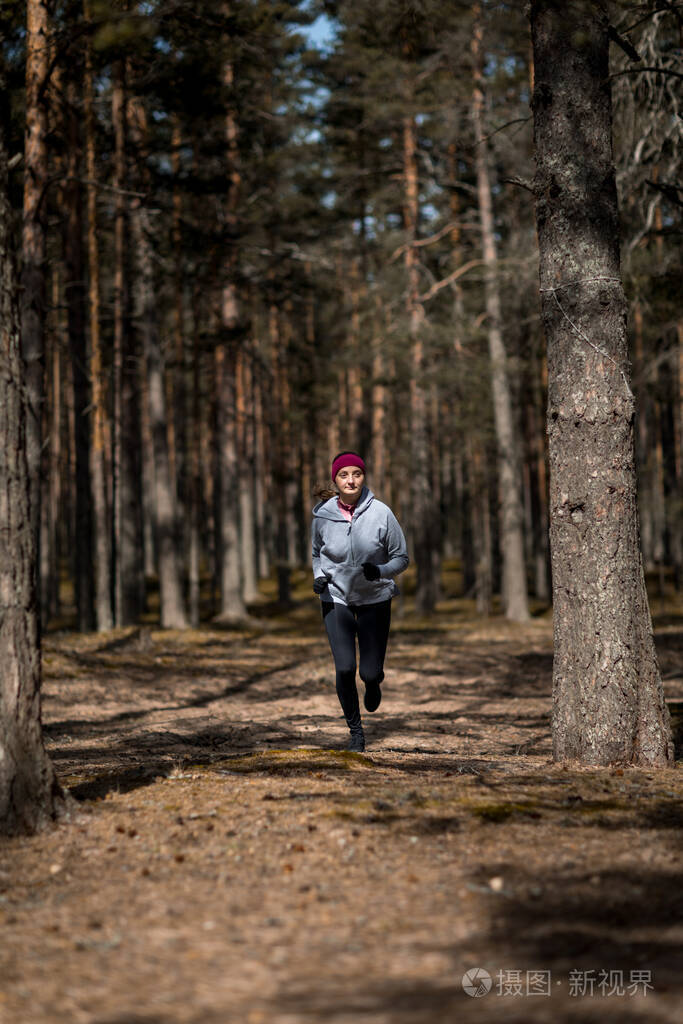 在树林里奔跑女孩在松林里从事体育运动