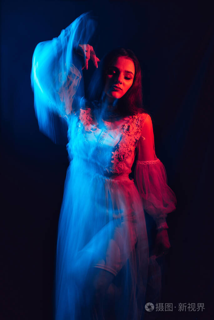 一个穿着裙子的模糊女孩在黑暗的背景下跳舞