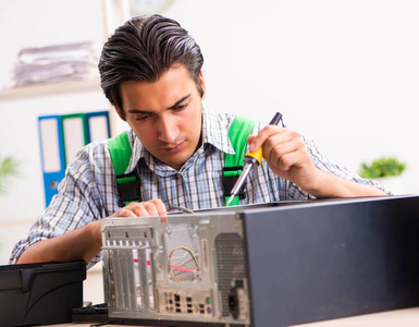 年轻工程师在办公室修理坏了的电脑照片