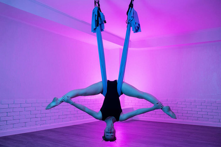 运动型年轻女子在瑜伽课上做重力式空中瑜伽伸展练习.身心平衡.照片