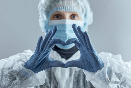 戴着医用面罩，戴着橡胶手套和西服的医务人员做了一个心形图。对抗冠状病毒。