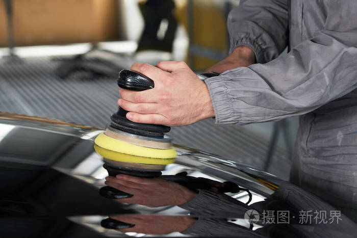 车间里用抛光机打磨黑色车身的人