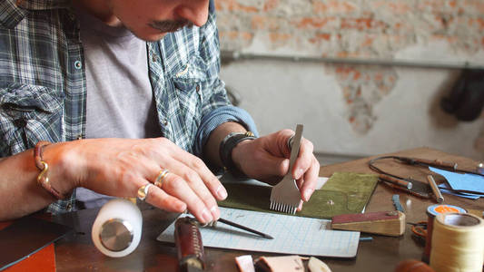 皮匠用一块真皮做钱包.一个在工作场所拿着工具的工匠照片