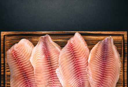 新鲜的白罗非鱼鱼片铺了一块木板.照片