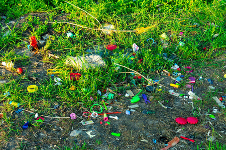 阳光下的草地上有一堆孩子们五颜六色玩具的垃圾。环保理念，乱扔垃圾。
