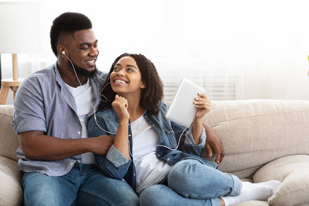 黑人夫妇在家里用数字平板电脑听音乐时共用耳机
