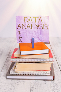 手写文本数据分析。概念意义将数字转化为分析结论预测堆积如山的书笔记本针衣夹彩色提醒白色木质。