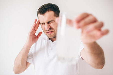 那个家伙拿着一个装着水和泡腾药片的模糊玻璃杯.头痛或疼痛.