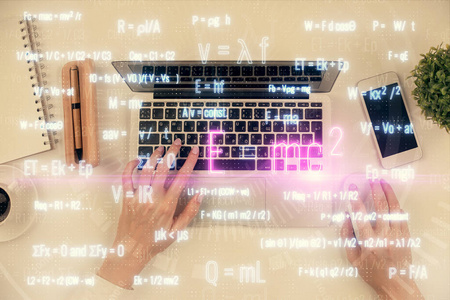 计算机和公式全息图绘制中女性双手的双重曝光。俯视图。科学概念。