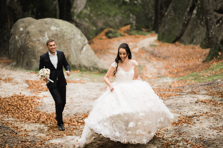 时髦的新婚夫妇。婚礼当天，新娘带着花束在公园里从新郎身边跑开