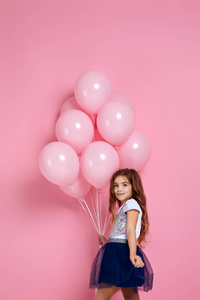 小女孩拿着粉红色的气球摆姿势