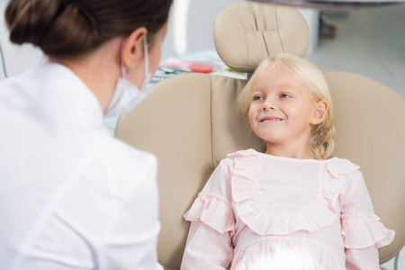 一个可爱的小女孩在牙医办公室和她的儿科医生说话