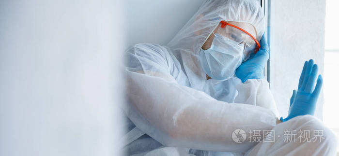 孤独隔离戴着医用面罩的男子望向窗外自我隔离冠状病毒大流行概念