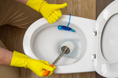 男人打扫厕所。在厕所当清洁工的管家。打扫一下厕所，保持清洁卫生。清洁马桶。清洁服务理念