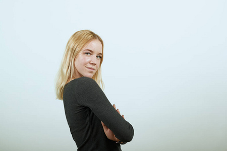 酷女孩双手合十抱在胸前,自信地看着镜头.侧身照片