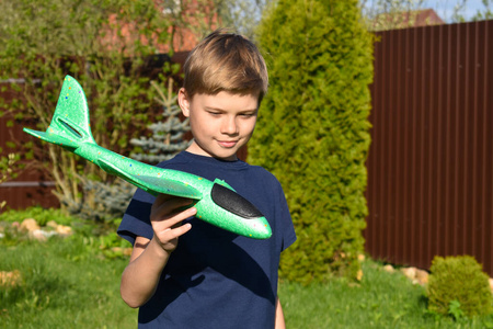 男孩把一架轻型飞机抛向空中。孩子们在草坪上玩耍。小男孩在花园里玩耍
