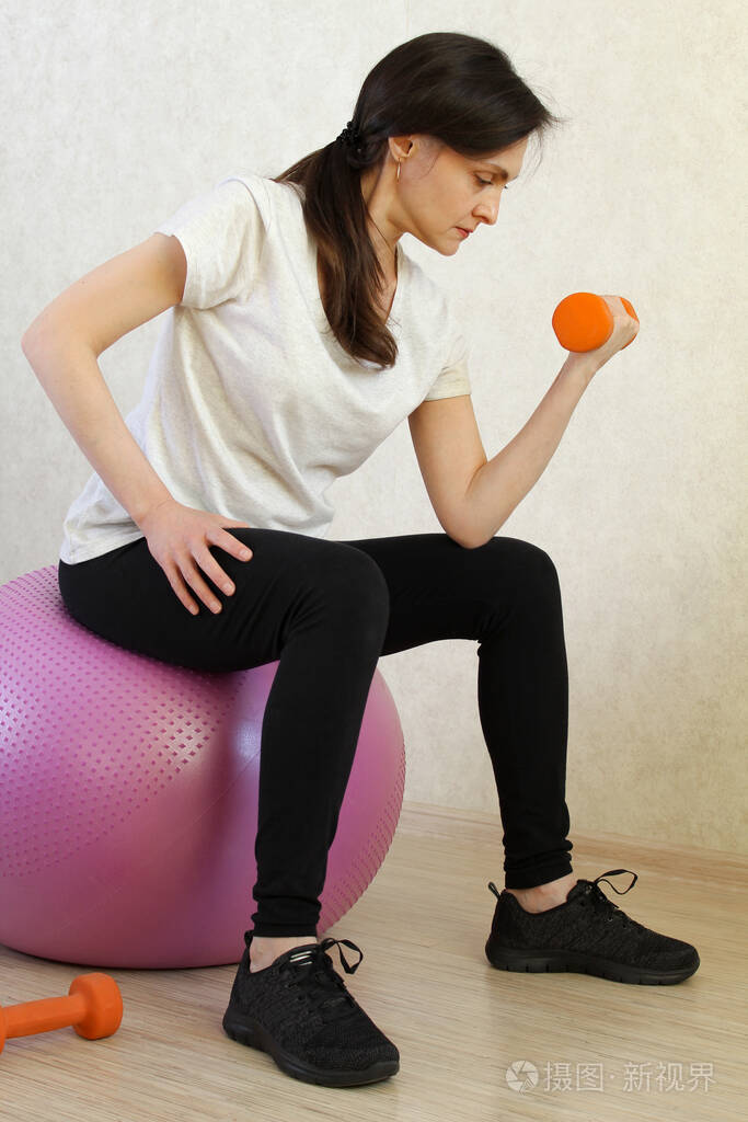 美女在家里用哑铃锻炼家庭健身训练停止冠状病毒covid19检疫时间