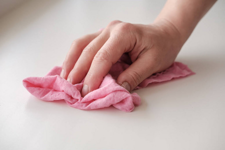 一只女人的手拿着一块抹布擦着一张白色的桌子.清洁的概念.家务.照片