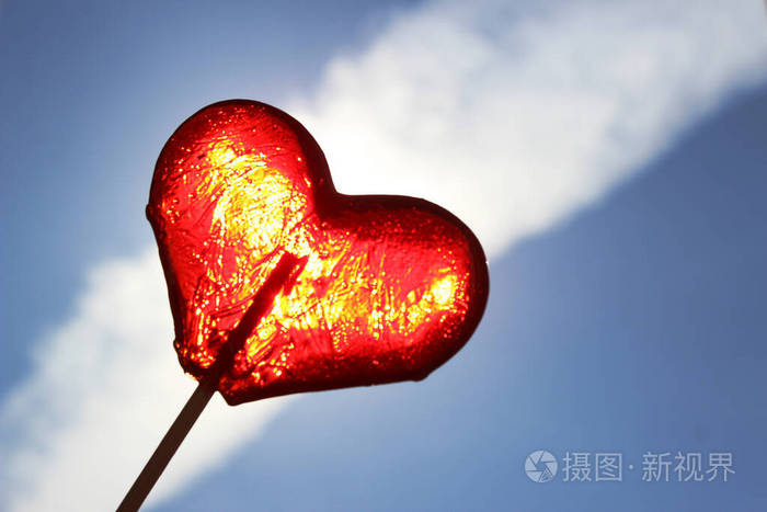 蓝色天空背景上的红色棒棒糖心形棒棒糖