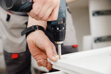 厨房安装,工人用刨花板拧紧螺栓组装箱体照片