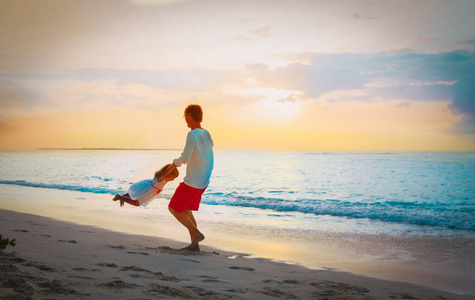 父亲和小女儿在日落海滩玩耍