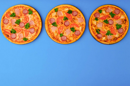 在蓝色背景上的比萨饼三个披萨在蓝蓝色的背景上.比萨饼隔离.