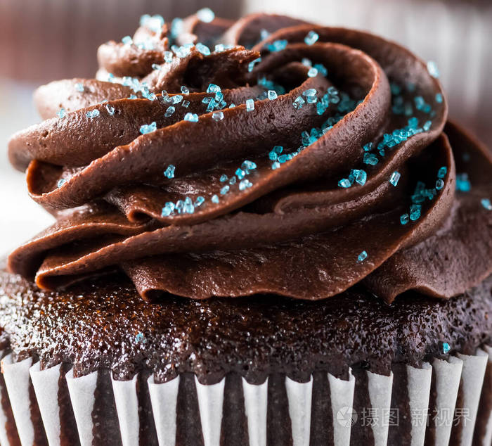 一个宏观特写视图顶部的巧克力糖霜巧克力蛋糕与蓝色洒