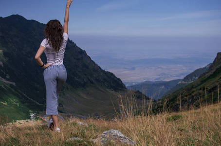 山顶上的女旅行者，手举在云端欣赏鸟瞰。旅行生活方式概念冒险快乐自由情感。高兴地。文本空间