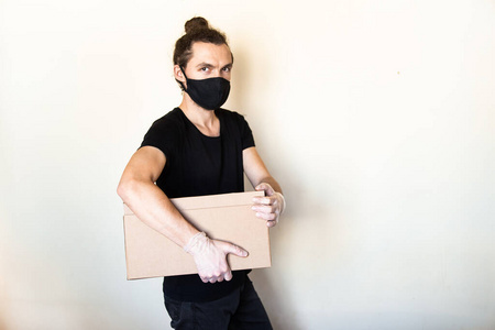 非接触食品德莱弗利概念。库卡斯送货员戴口罩，手套拿着纸板箱。大流行性冠状病毒2019 ncov期间的递送服务。