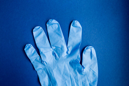 预防冠状病毒。蓝色背景上的特写医用防护手套。危险防护COVID19