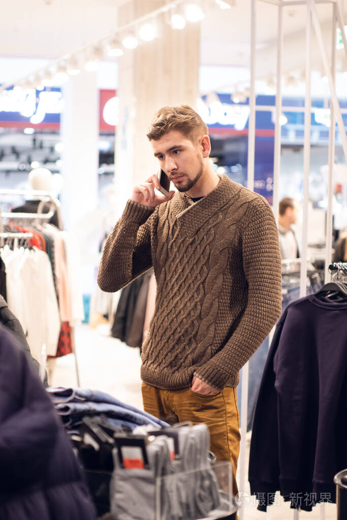 现代人买衣服用智能手机聊天年轻英俊的白人客户