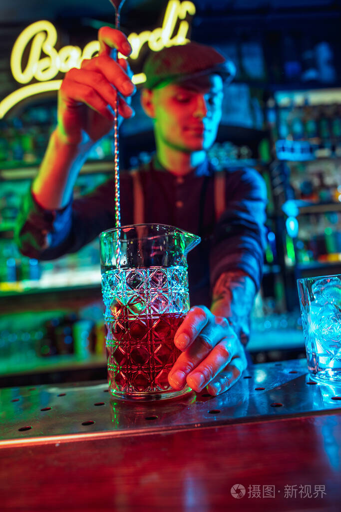 酒吧男招待在五彩霓虹灯下完成酒精鸡尾酒的准备