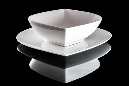 Empty ceramic dishes for dinner isolated on black. White square 