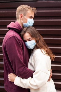 一对年轻夫妇戴着防护口罩在城市里拥抱