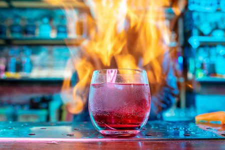 酒精鸡尾酒饮料饮料的特写镜头，背景是火焰的五彩霓虹灯