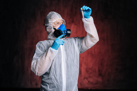 医护人员穿着防护服,护目镜和呼吸器,手持试管.照片