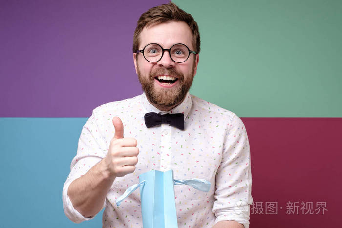 一个带着礼物的高加索男人被一个惊喜吓了一跳做出了一个赞许的手势