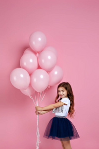 小女孩拿着粉红色的气球摆姿势