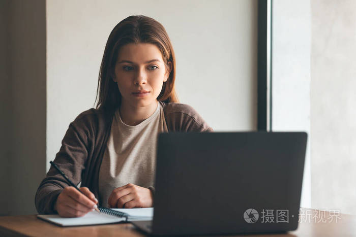 专心听课的小女孩一边写笔记一边听免费网络研讨会